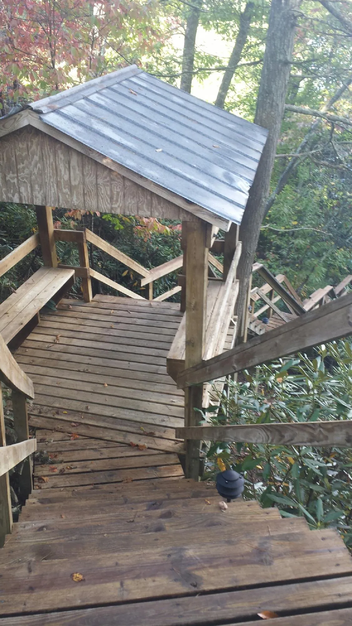 Metal roofed shelter over wooden steps on a wooded walkway — Skylight Repair & Installation work by our crew in Laurel Hill